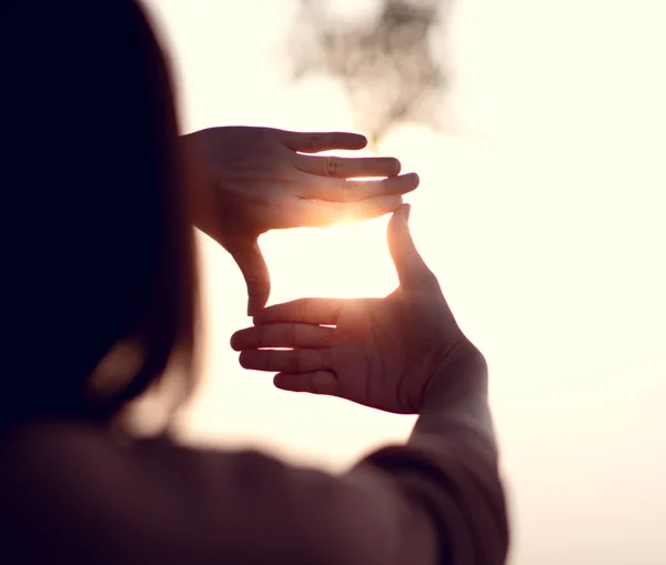 Une femme regardant la lumière du soleil avec ses mains